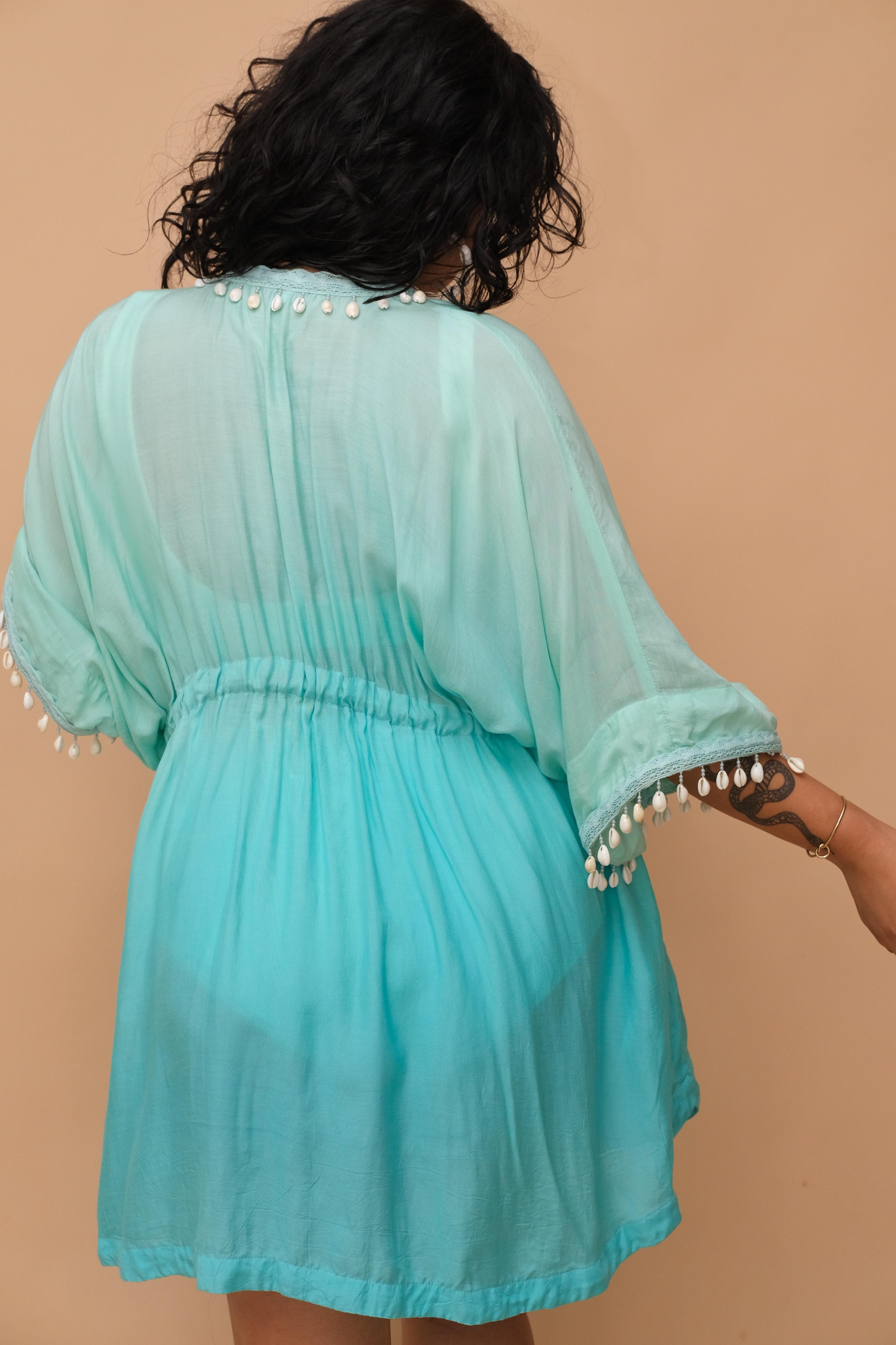 Plus size woman wearing a light blue kaftan with white embellishments 