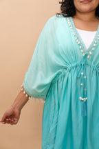 Woman wearing a turquoise dress with white embellishments 