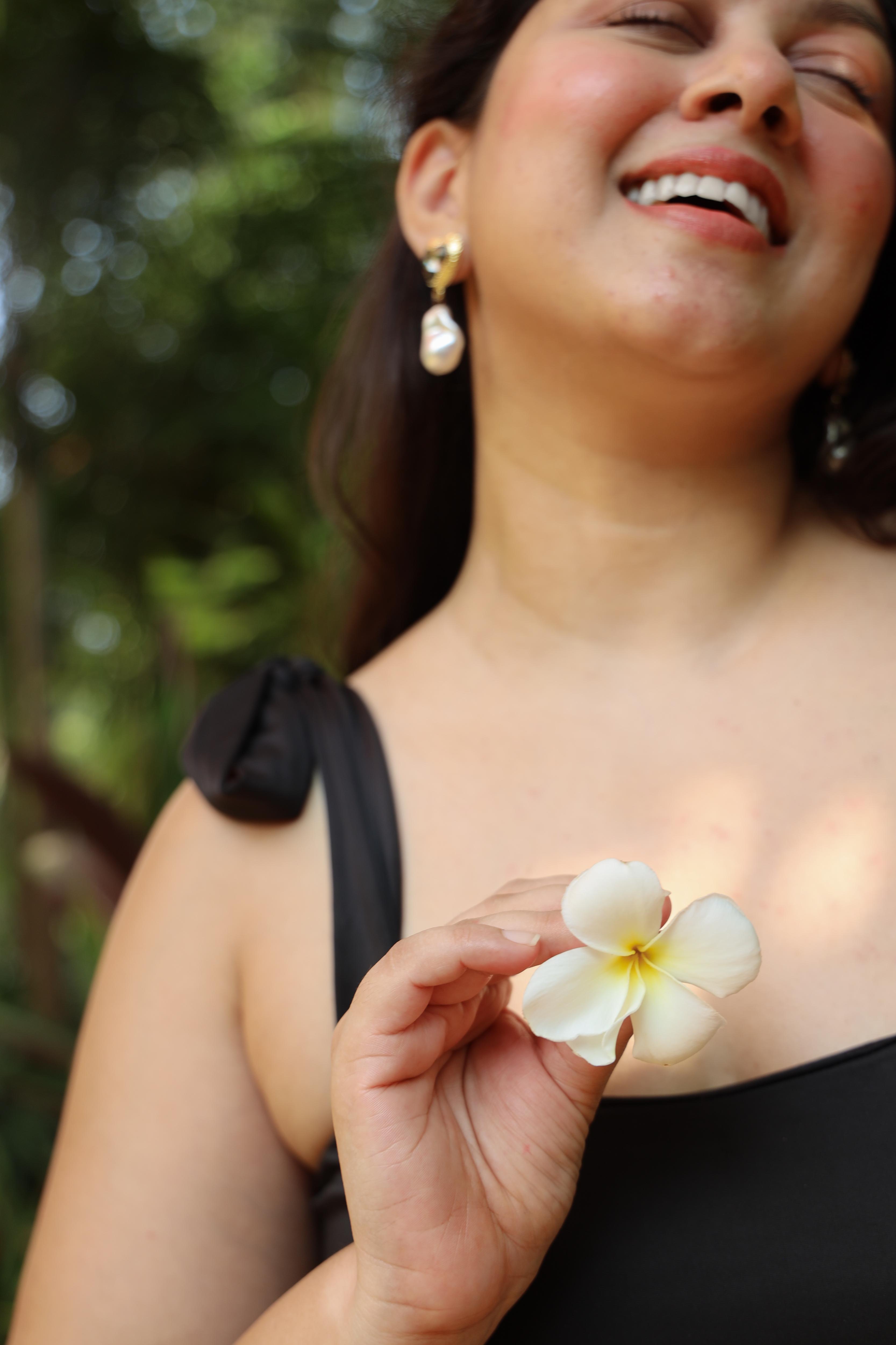 Woman holding a white flower in a round neck bikini top