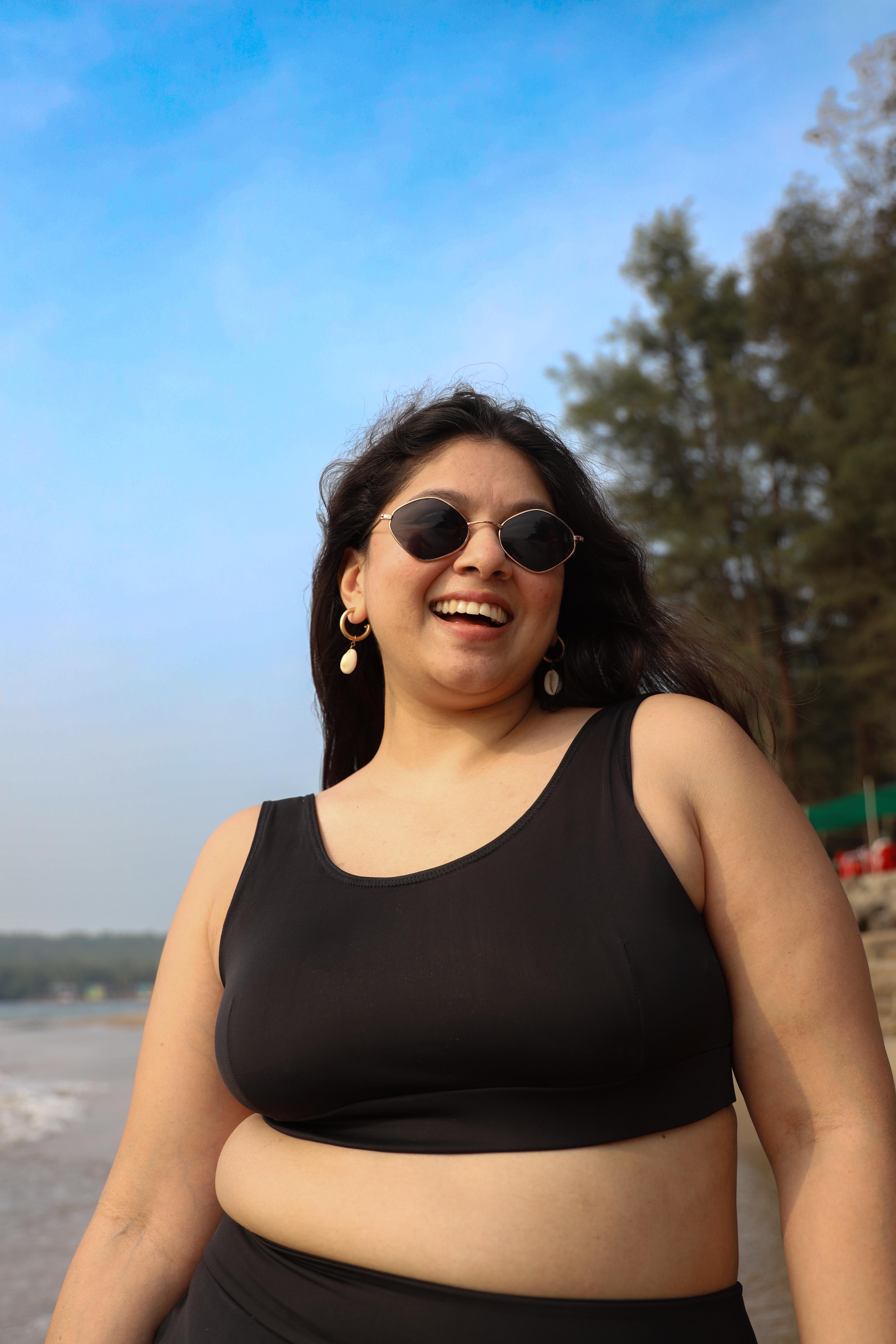 Curvy woman wearing sunglasses and a black round neck top 