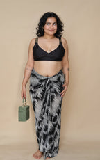 Woman wearing a black bikini top and patterned skirt holding a green bag