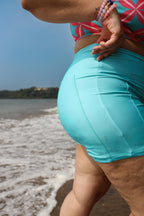 Plus size curvy wearing a turquoise swimsuit 