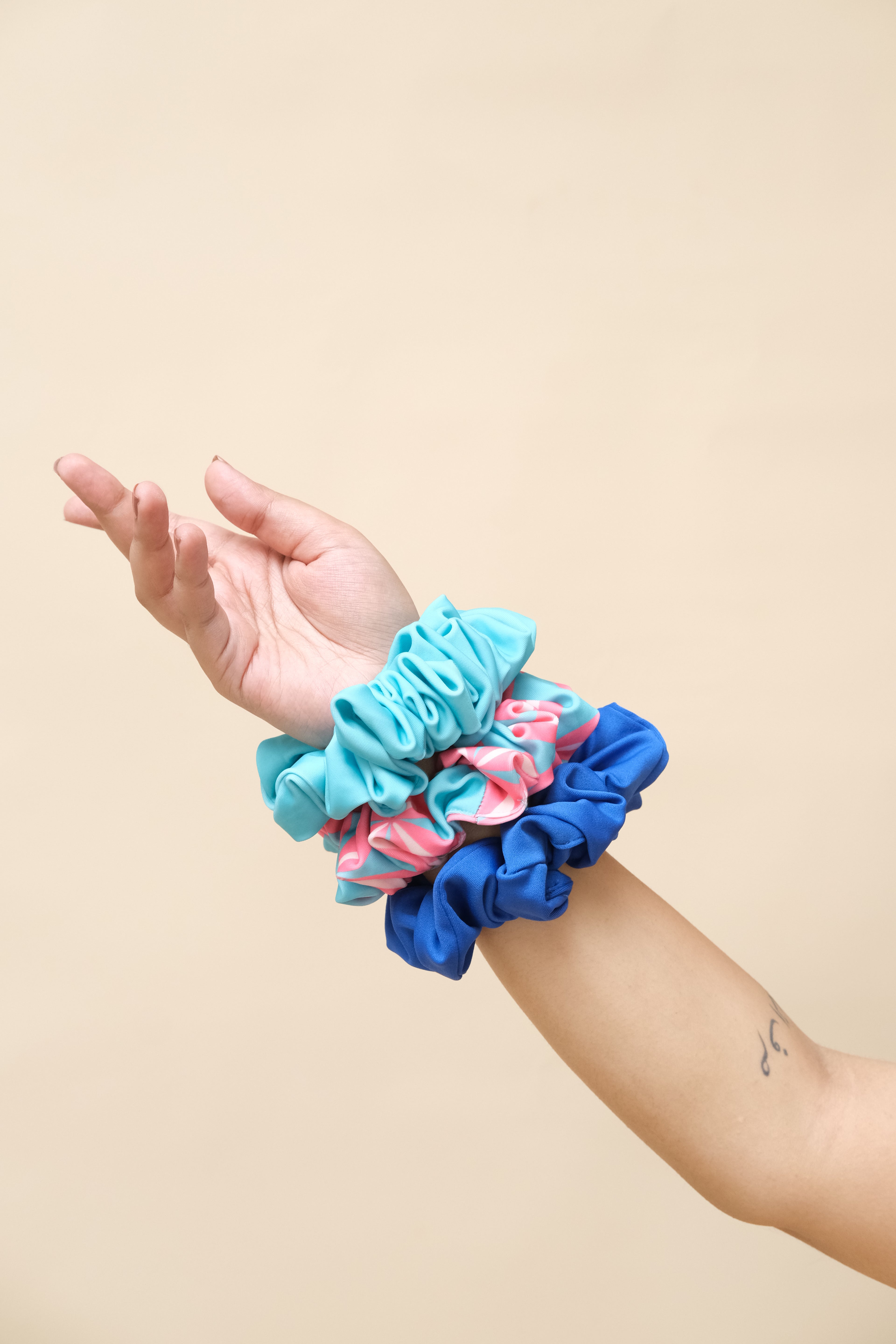 Hand wearing a blue scrunchie with pink and white pattern 