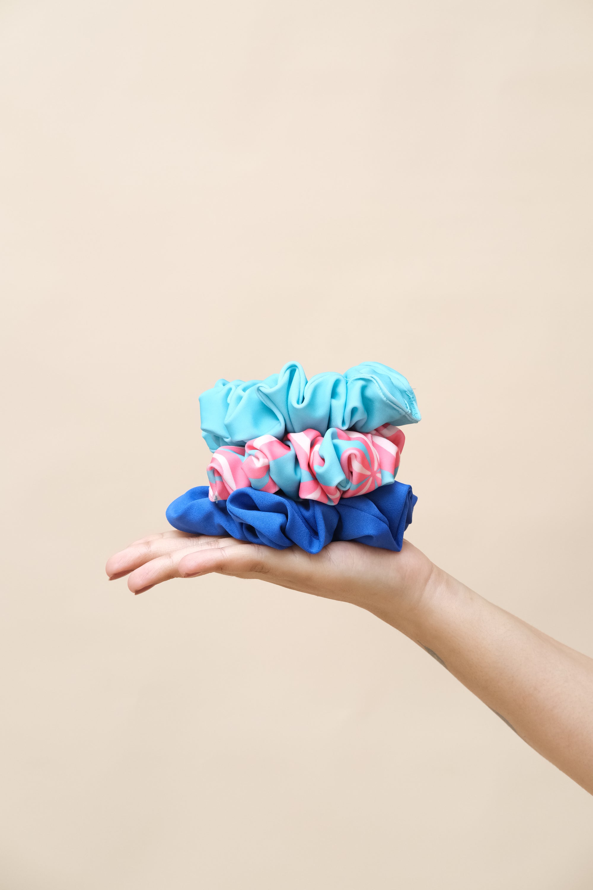 Hand holding three colorful scrunchies