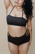 Woman wearing a black bikini with gold accents 