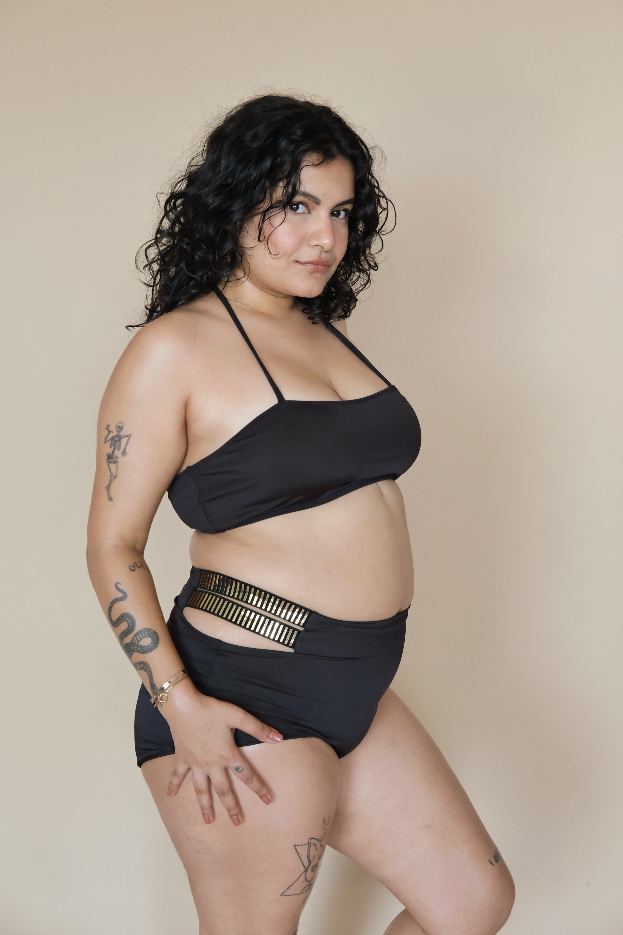 Woman wearing a black bikini bottom with gold accents