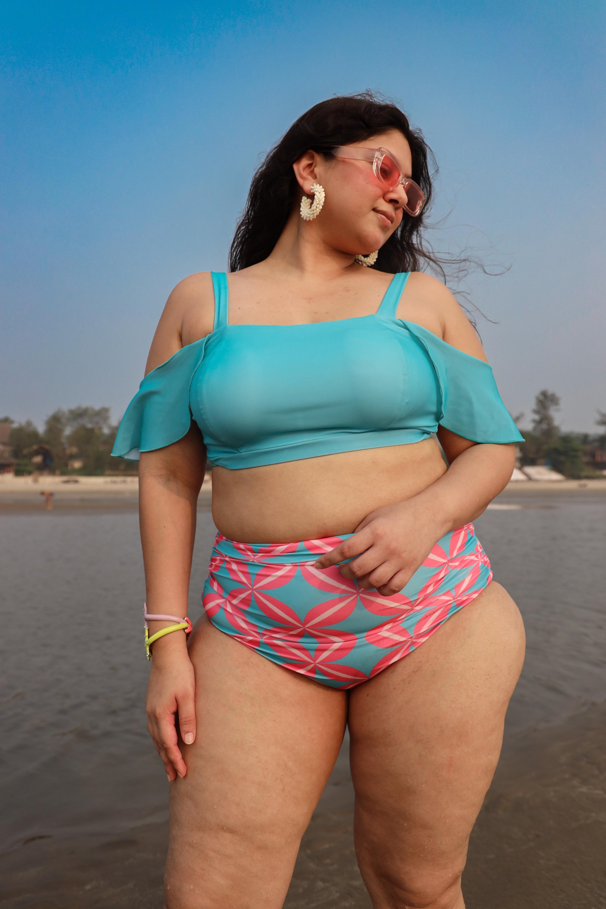 Woman in a blue top and pink patterned high-waisted bikini set
