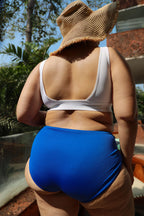 Curvy Asian woman wearing a white bikini top and blue bottoms 